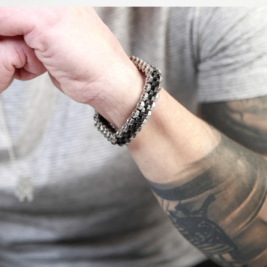 Stainless steel bracelet with a mix of black and silver hex nuts .